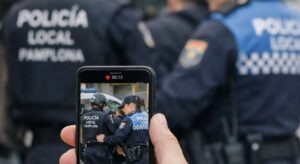 La grabación de actuaciones policiales por particulares: límites legales y criterios judiciales imagen ficticia de una persona grabando con su móvil unas actuaciones policiales